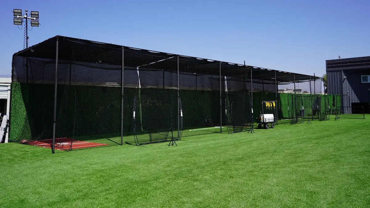 Row of netted outdoor batting cages at MF Training SB under a clear sky